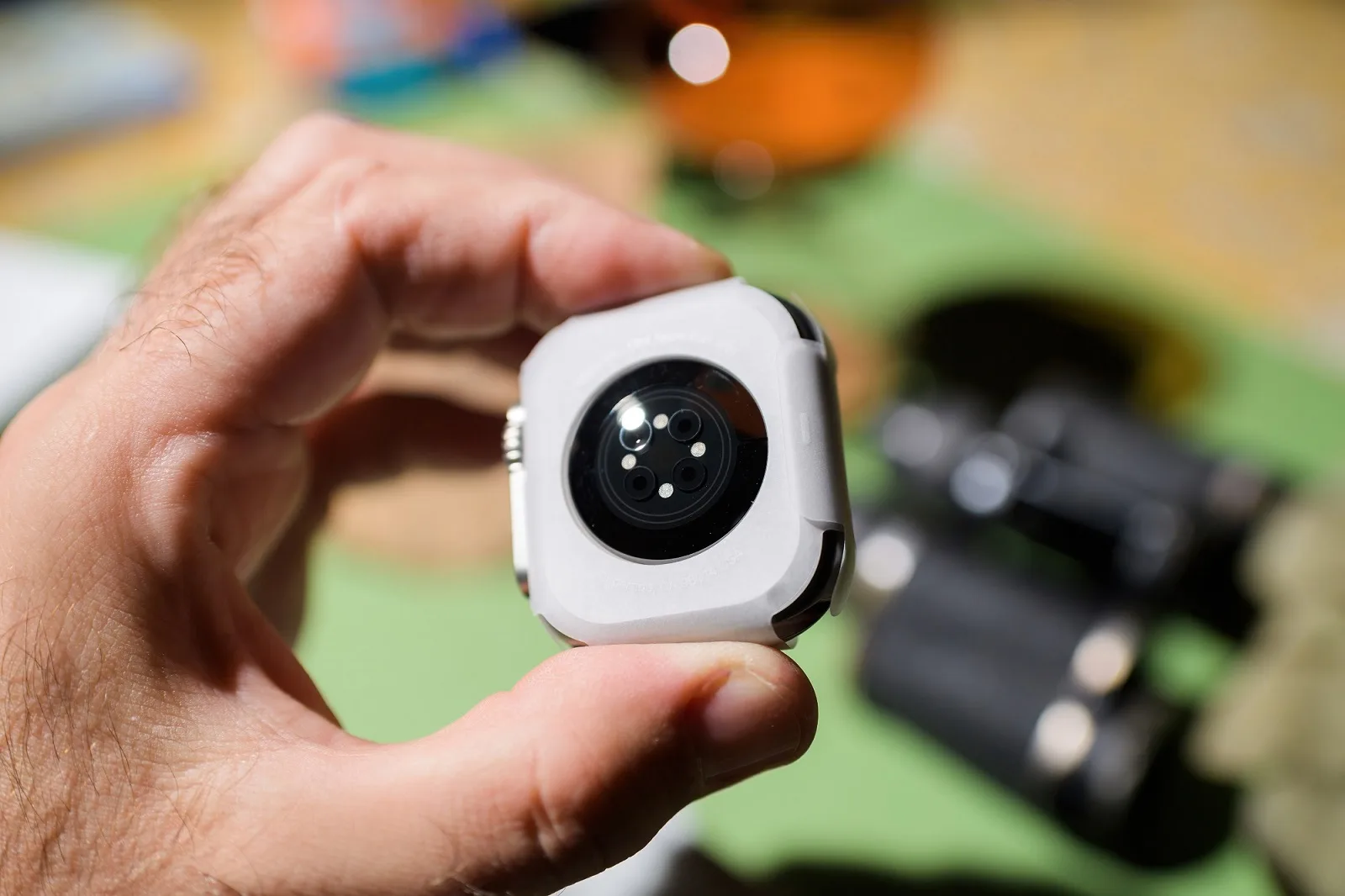 Male Hand Holding A Smart Watch with Different Sensors on the Back