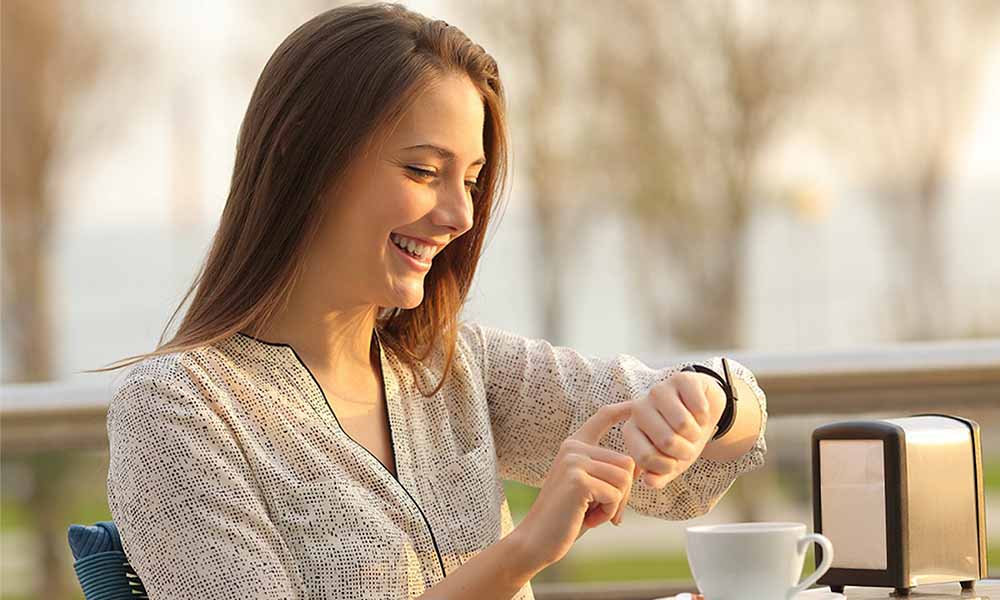 A Happy Lady Manages Her Daily Schedule with A Smartwatch in A Coffee Shop