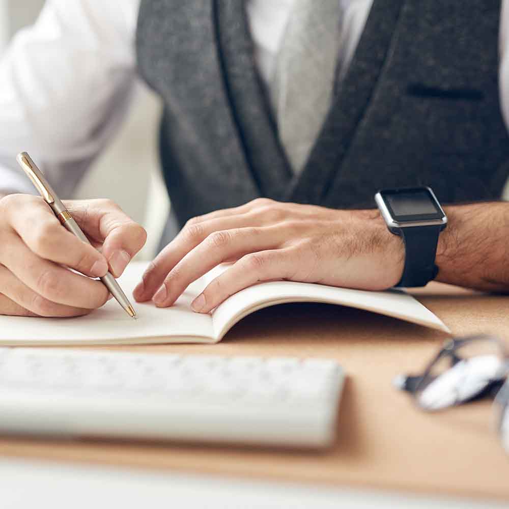 A Man Writing Wearing a Smart Watch on His Left Wrist