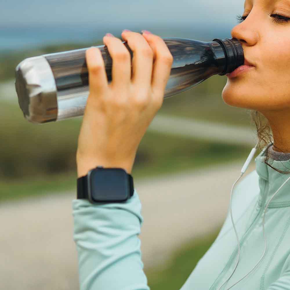 A Woman with a Smart Watch on Her Wrist Is Drinking Water